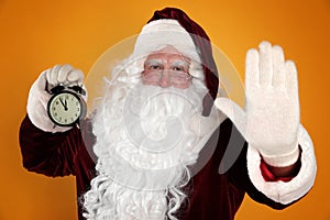 Santa Claus holding alarm clock on yellow background. Christmas countdown