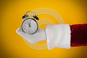 Santa Claus holding alarm clock on yellow background, closeup. Christmas countdown