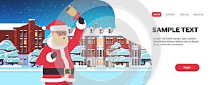 Santa claus holding bell merry christmas happy new year holiday concept winter houses snowy town street greeting card