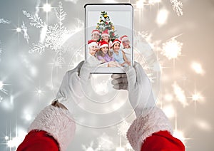 Santa claus holding a digital tablet with photo of christmas family