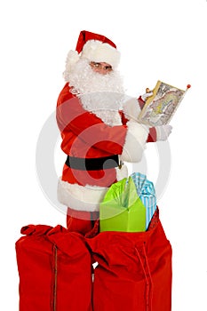 Santa Claus holding map, sacks of presents on the ground