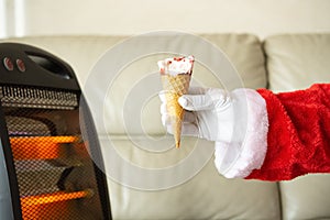 A santa claus holding a strawberry flavor ice cream cone with a bite in front of an electric heater