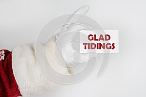 Santa Claus holds a business card with the text - GLAD TIDINGS