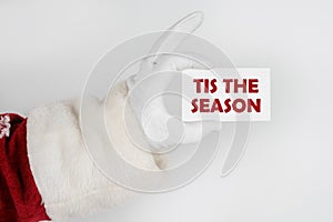 Santa Claus holds a business card with the text - TIS THE SEASON photo