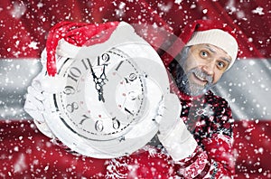 Santa Claus holds a clock in his hands against the background of the flag of Austria