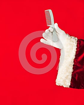 Santa Claus holds a comb in his hand. Hair care concept, hair salon, etc. Red background, with copy space