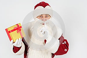 Santa Claus holds a gift in his hand, and the other makes a hand gesture - quietly. Isolated on white