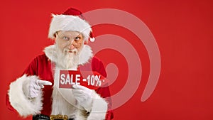 Santa Claus Holds Sign With Inscription Sale -10 off, Points His Finger at an Empty Space Mock up and Looks at Discount