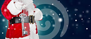 Santa Claus with home key on winter background