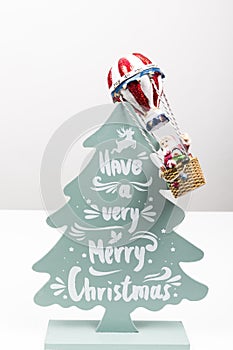 Santa Claus in Hot air balloon flight up to a wood green tree, on white background