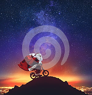 Santa Claus on a little bike on the peak of a mountain under the stars