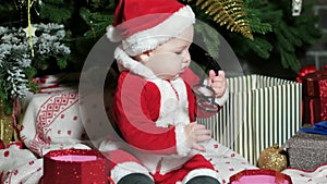 Santa Claus little boy, baby in Santa suit, playing with glasses, child sits in the carnival costumes, Christmas