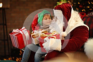 Santa Claus and little boy with Christmas gifts