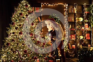 Santa Claus with little boy having fun by the fireplace while decorates Christmas tree