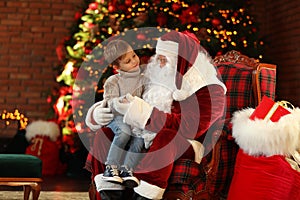 Santa Claus and little boy near Christmas tree