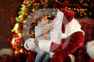 Santa Claus and little boy near Christmas tree