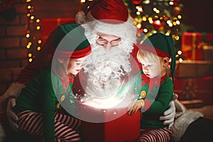 Santa Claus and little elves with magic gift for Christmas