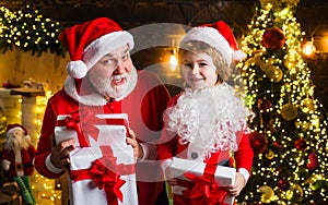 Santa Claus and little helper with Christmas present. New year gift. Happy childhood. Christmas background.