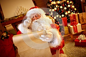 Santa Claus looking at long list with children desire photo