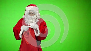 Santa Claus looks into the bag with gifts and touches the head. chroma key. slow motion