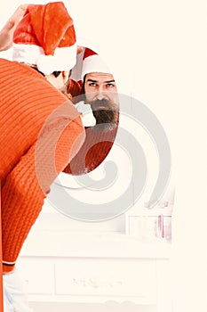 Santa Claus looks into mirror. Guy leans down to mirror.
