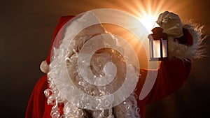 Santa Claus on a magical background with a flashlight in his hand. New Year and Christmas concept. Santa Claus holds a