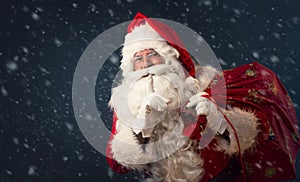 Santa Claus making a silence gesture, on dark background