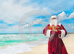 Santa Claus with many golden gifts on sea beach