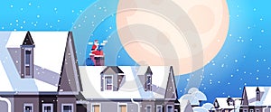 Santa claus in mask sitting on roof using laptop happy new year merry christmas holidays celebration concept