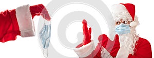 Santa Claus with a medical mask on pointing with both hands at a medical mask given to him by another Santa. Isolated, white