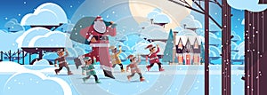 santa claus with mix race elves in night snowy forest happy new year merry christmas holidays celebration concept