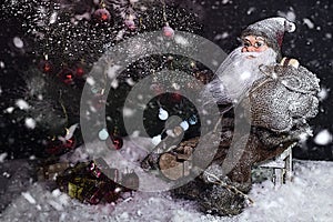 Santa Claus Outdoors Beside Christmas Tree in Snowfall Carrying Gifts to Children