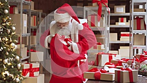 Santa Claus packing present gift boxes in sack bag preparing fast xmas delivery.