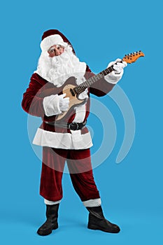 Santa Claus playing electric guitar on blue background. Christmas music