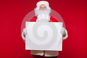 Santa Claus pointing in blank advertisement banner isolated on red background with copy space