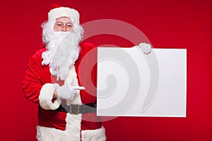 Santa Claus pointing in blank advertisement banner isolated on red background with copy space