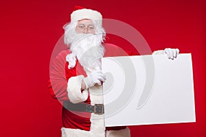 Santa Claus pointing in blank advertisement banner isolated on red background with copy space