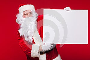 Santa Claus pointing in blank advertisement banner isolated on red background with copy space