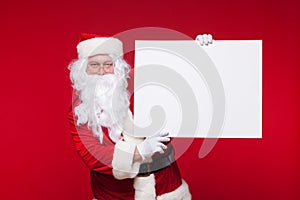 Santa Claus pointing in blank advertisement banner isolated on red background with copy space