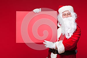 Santa Claus pointing in blank advertisement banner isolated on red background with copy space red leaf