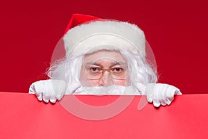 Santa Claus pointing in blank advertisement banner isolated on red background with copy space red leaf