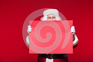 Santa Claus pointing in blank advertisement banner isolated on red background with copy space red leaf