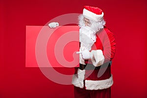 Santa Claus pointing in blank advertisement banner isolated on red background with copy space red leaf