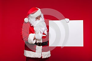 Santa Claus pointing in blank advertisement banner isolated on red background with copy space