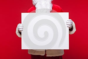 Santa Claus pointing in blank advertisement banner on red background with copy space