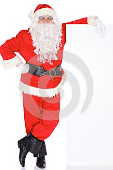 Santa Claus pointing on blank white wall, advertisement banner with copy space. Isolated on white background. Full