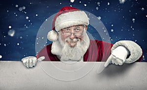 Santa Claus pointing in white blank sign with smile