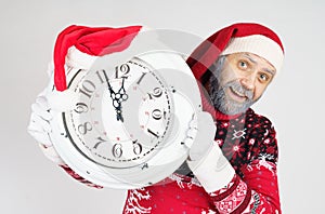 Santa Claus points to the clock before Christmas. Santa hat on the clock