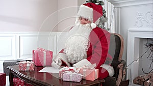 Santa Claus preparing presents for children and checking the gift list