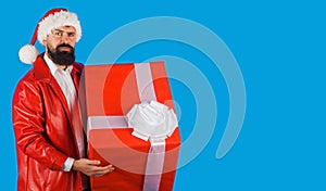 Santa Claus with present. Christmas time. Bearded man in Santa hat with gift box. New year advertising. Copy space.